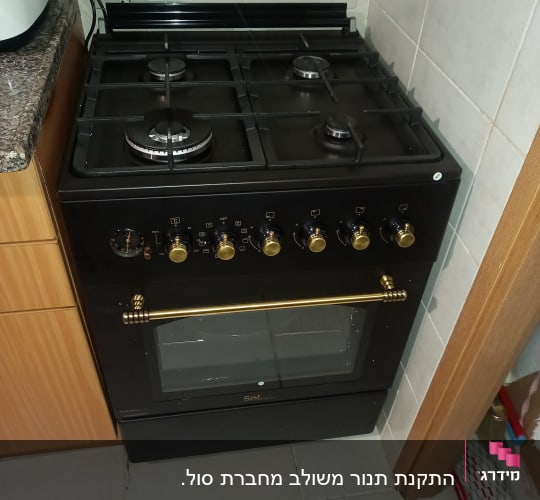 תנור גז שחור עם כפתורים מוזהבים